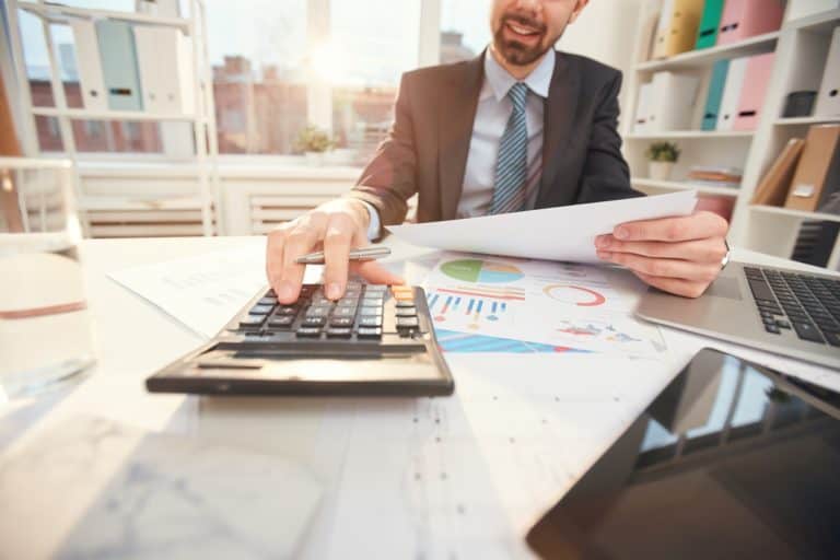 Smiling Businessman Calculating Finances Closeup